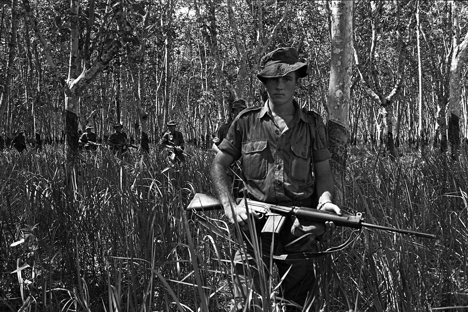Vietnam War, Soldier Portrait, Combat Uniform, U.S. Military, Boonie Hat, Camouflage Pattern, M16 Rifle, Infantry Patrol, Forested Terrain, Mangrove Forest, Black and White Photo, Military Operation, Search Operation, Armed Forces, War Photography, Historical Military, Jungle Warfare, Tactical Gear, Soldier's Stance, Combat Environment