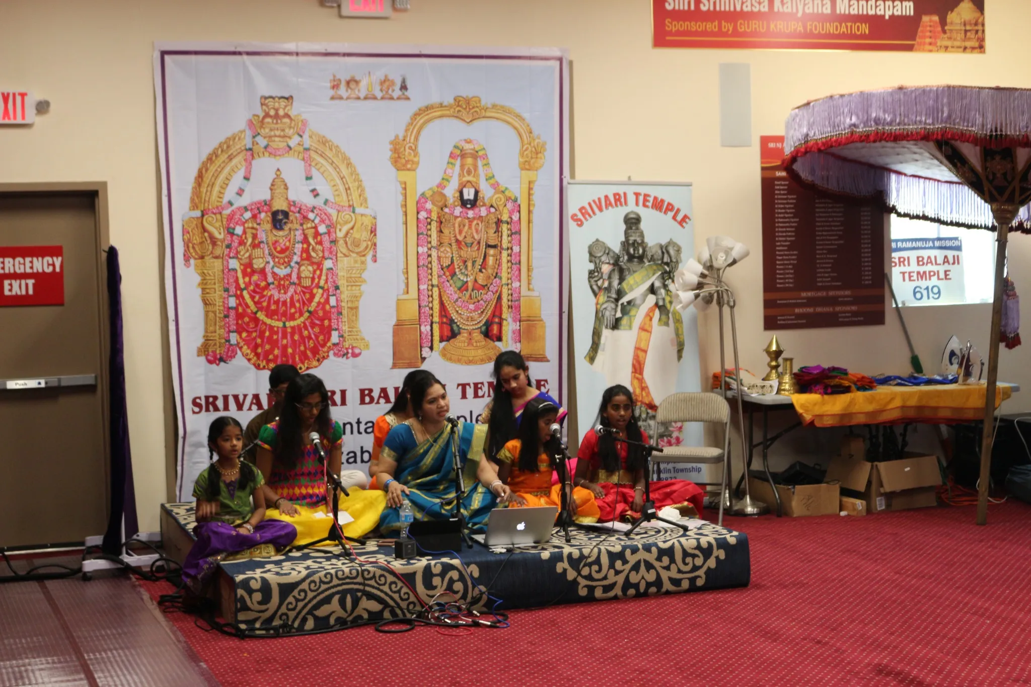Ramanujar temple, 1000-year celebration, cultural event, Hindu music performance, traditional Indian attire, religious celebration, temple festival, Indian traditions, devotional recital, community gathering, Hindu deities, temple banner